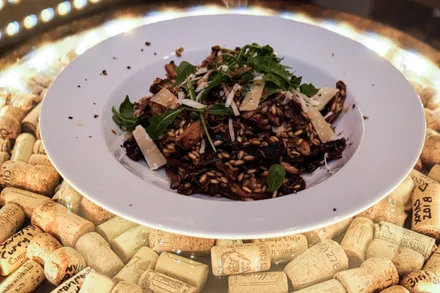 A bowl of mushroom risotto topped with parmesan, rocket leaves, and a shaving of truffle.