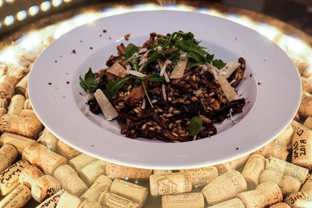 A bowl of mushroom risotto topped with parmesan, rocket leaves, and a shaving of truffle.