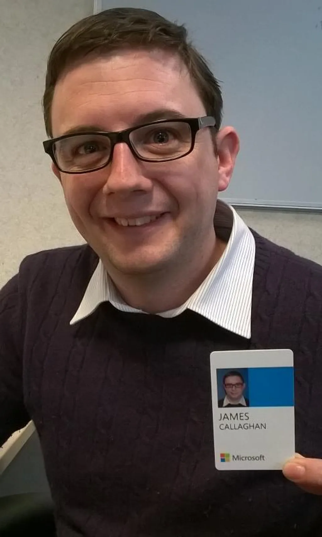 James holding his new Microsoft ID badge, smiling, in an office.