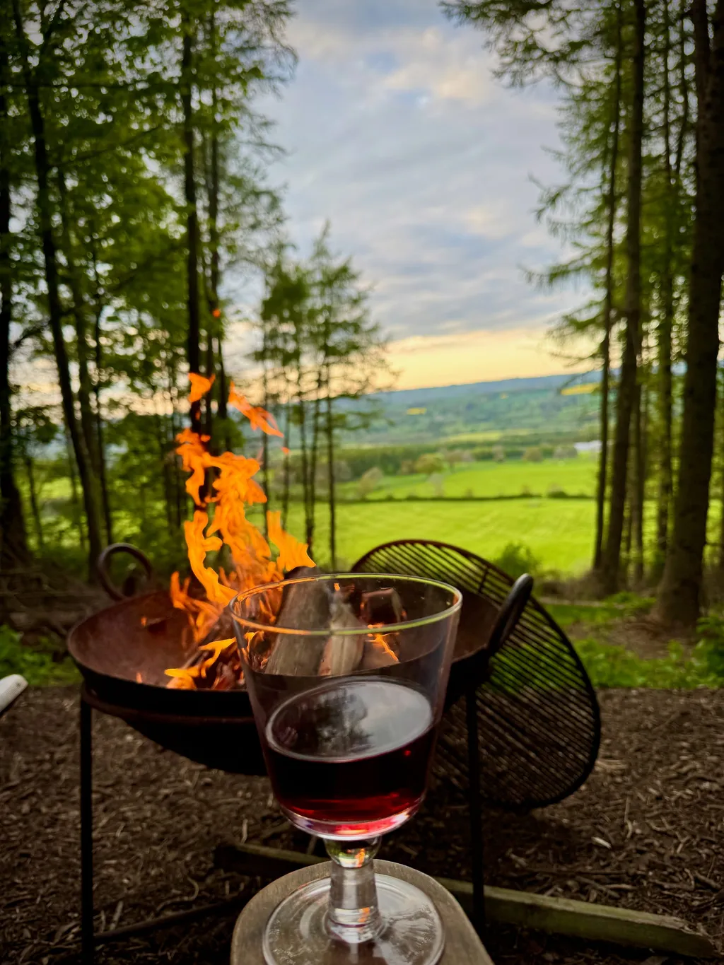 A glass of red wine beside the fire bowl on the cabin deck, the Yorkshire valley darkening behind.