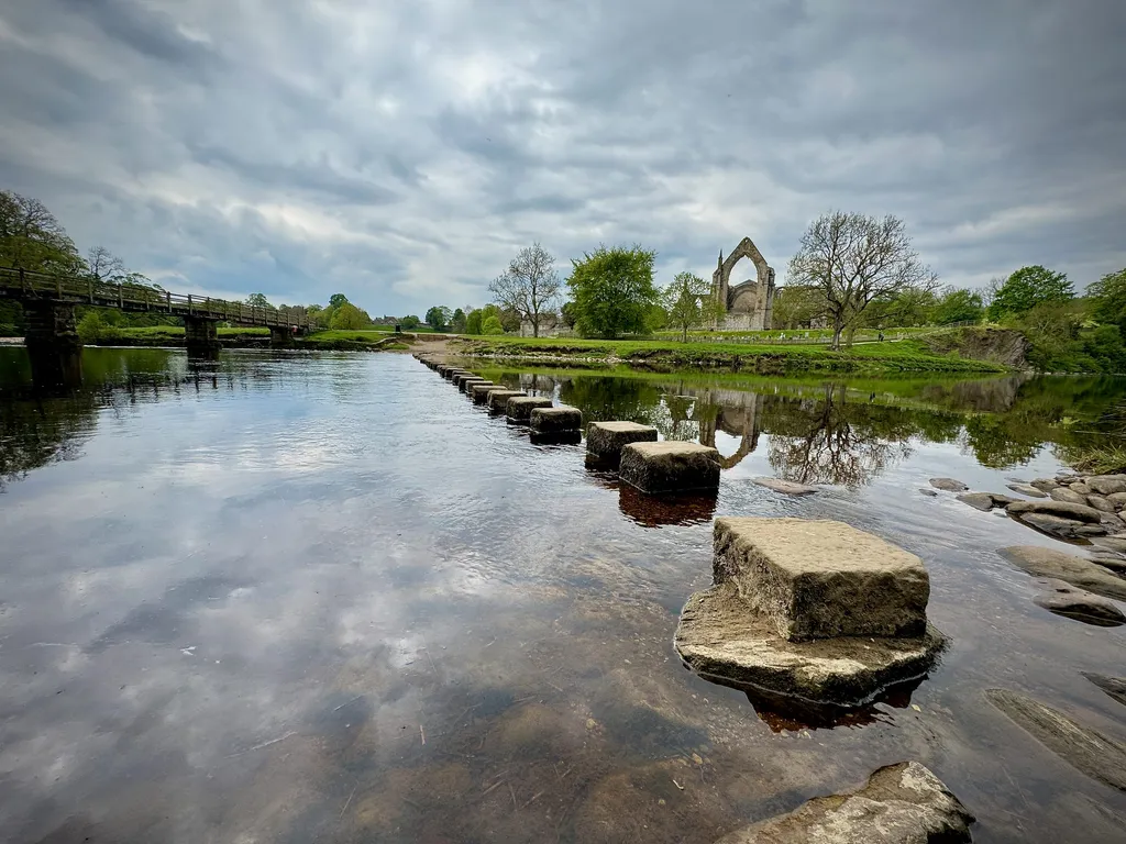 The stepping stones at Bolton Abbey stretching across the wide shallow river, reflected in the still water.